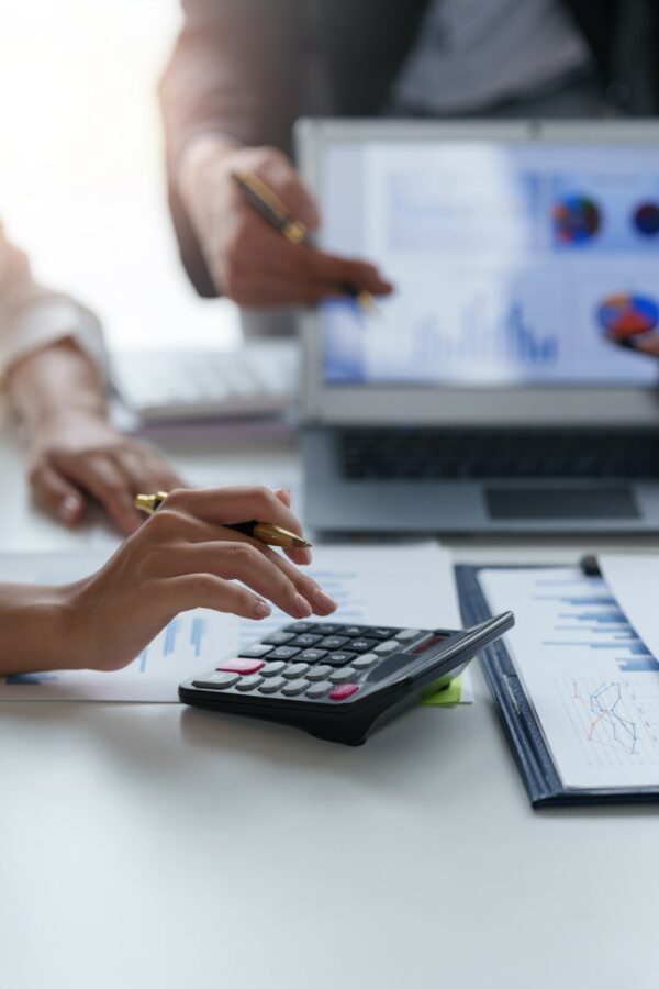 Business people point to graphs and charts on laptop to present